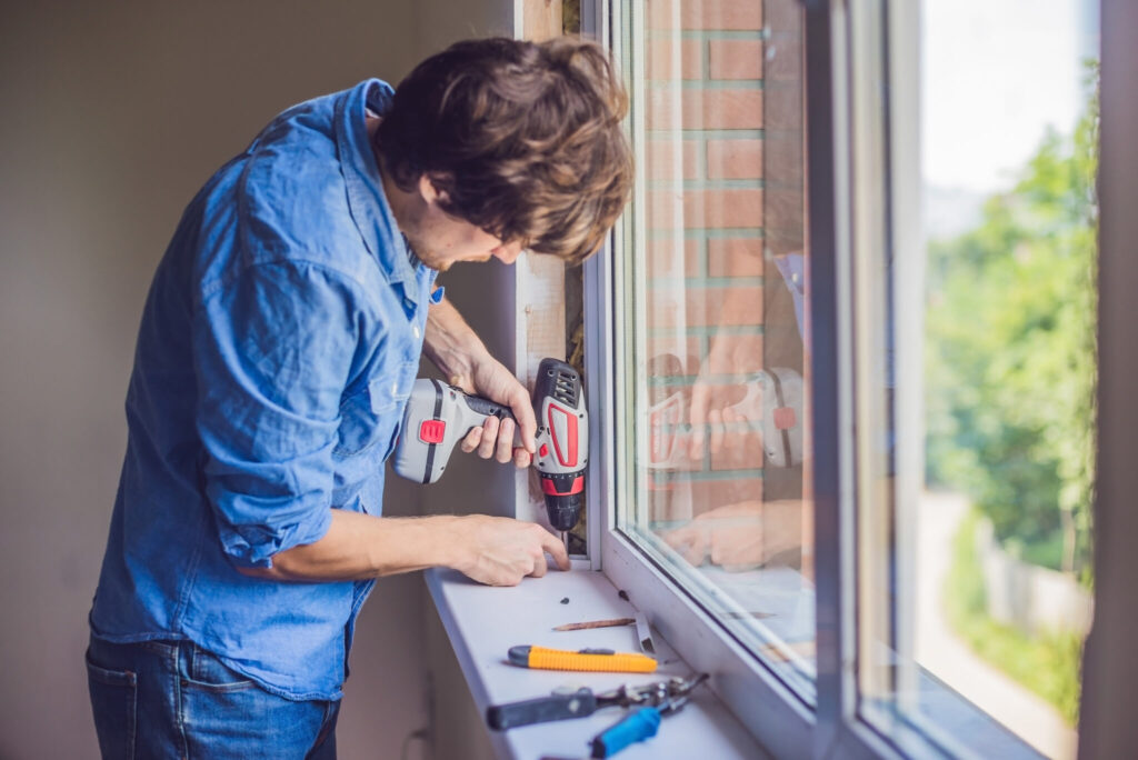 A glazier working along the inside edge of a window frame