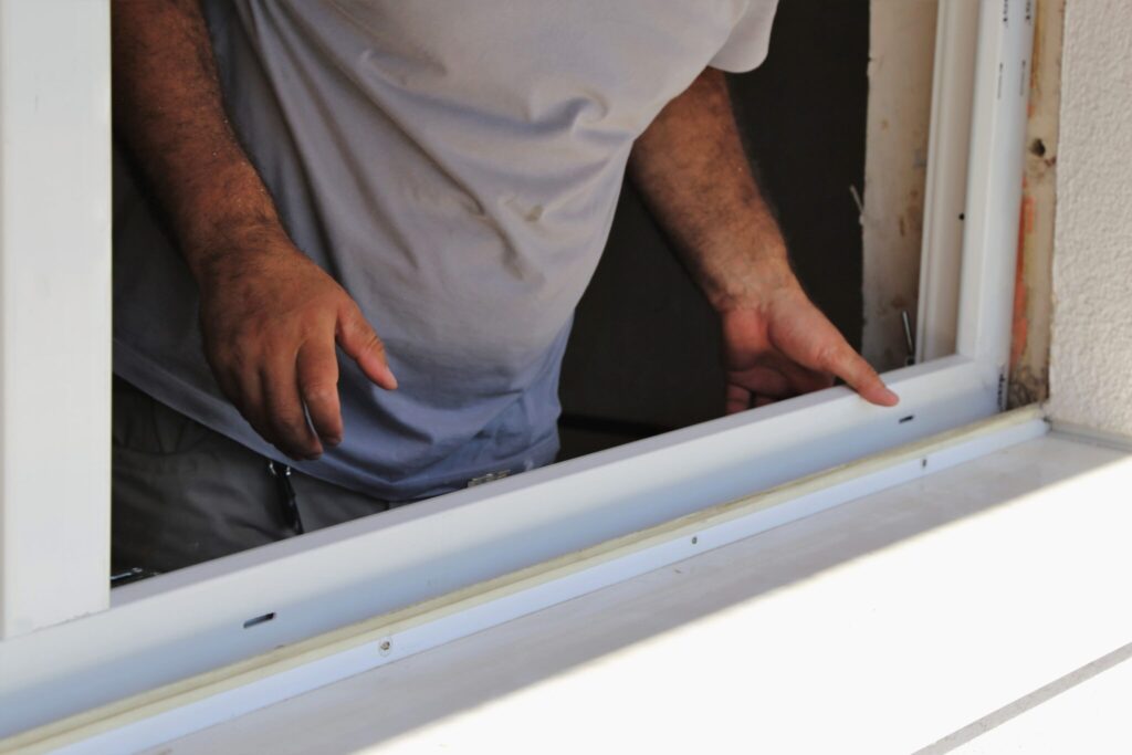 Hands guiding a pane into a window frame